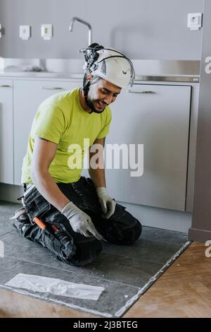 Tiler installing tiles on kitchen floor Stock Photo
