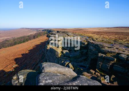 On top of Stanage Edge looking down in to Robin Hood's cave nestled on the cliff face. Stock Photo