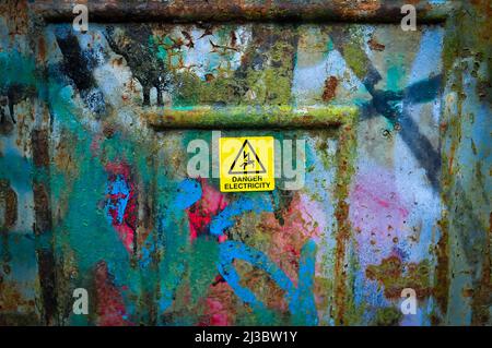 Yellow sign danger electricity on metal can outside in England  Stock Photo