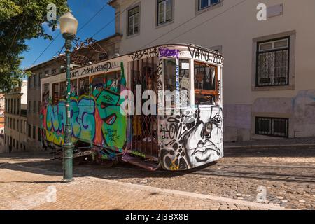 Vintage funicular, totally covered with graffity, in a steep street in old town of Lisbon, Portugal Stock Photo