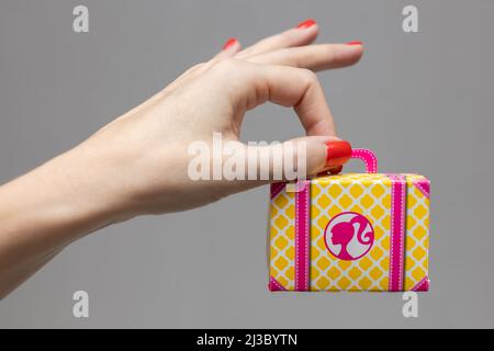 female hand holding a toy cardboard suitcase Stock Photo