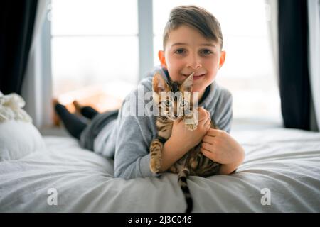 Bengal cat in the bed room with child boy Stock Photo