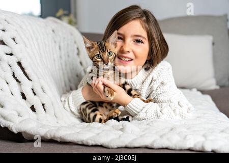 Bengal cat in the living room on the couch with child Stock Photo