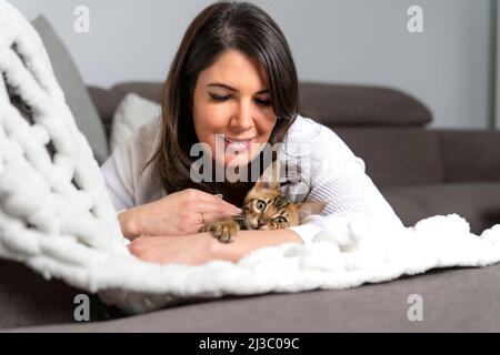 Bengal Cat in the living room on the couch with a woman Stock Photo