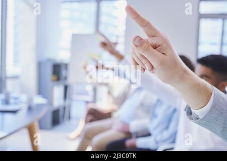 We have questions. Cropped shot of a group of businesspeople raising their hands during a meeting. Stock Photo