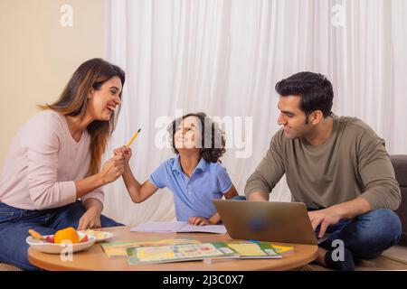 Mother kidding with her son and father using laptop Stock Photo