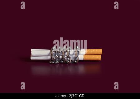 Nicotine addiction. Three cigarettes rewound by a chain  Stock Photo