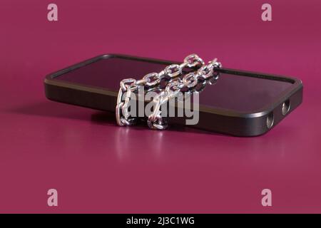 Nomophobia. The smartphone is rewound by a chain  Stock Photo