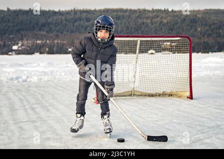 Boy playing hockey on a beautiful lake Stock Photo