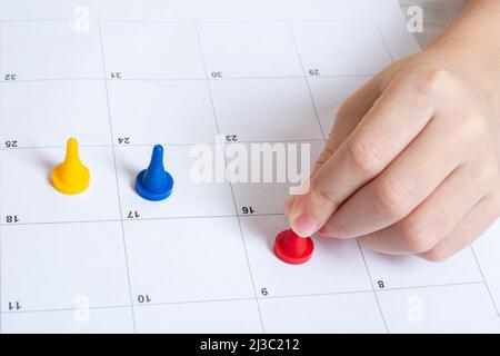 Board game and children's leisure concept - a child's hand moves a game chip on the field. Multi-colored chips on a lined field. Minimalism. Family le Stock Photo