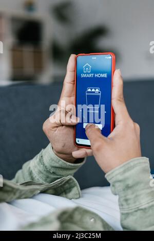 Man using IOT mobile phone app at home Stock Photo