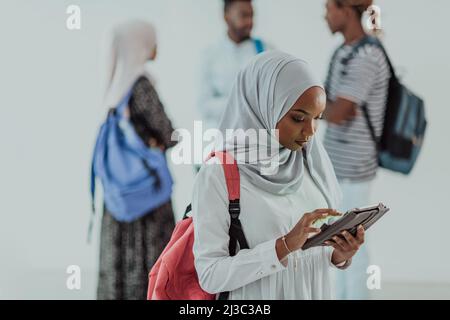 African female student with group of friends in background wearing traditional Islamic hijab clothes. Selectve focus  Stock Photo