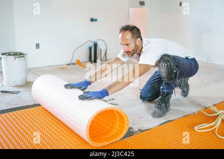 Man worker install orange roll membrane waterproofing on the floor Stock Photo