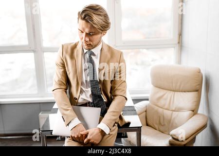 Handsome pensive caucasian businessman hold mobile phone distracted from work conference online, self-employed man solve business issues, have a break Stock Photo