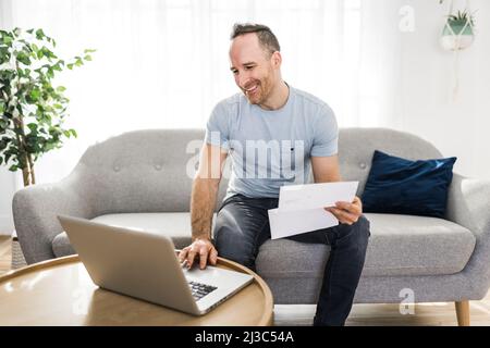 Handsome man paying online using a laptop Stock Photo