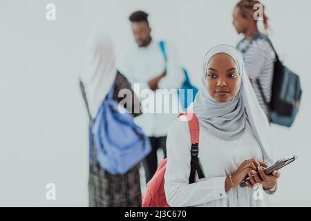 African female student with group of friends in background wearing traditional Islamic hijab clothes. Selectve focus  Stock Photo