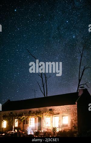 Leave the lights on, Im coming home. Shot of a house in the countryside on a dark starry night. Stock Photo