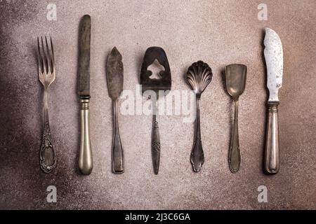 Top view of vintage silver cutlery or silverware on brown concrete background Stock Photo