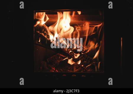 Bright colored dancing flames in fireplace. Close up of burning firewood. Cozy warm background Stock Photo