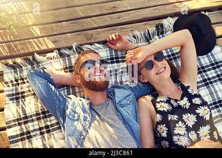 Best summer day ever. Shot of an affectionate young couple lying on a blanket outdoors. Stock Photo