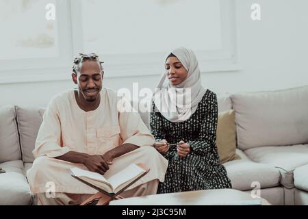 African Muslim couple at home in Ramadan reading Quran holly Islam book. Stock Photo