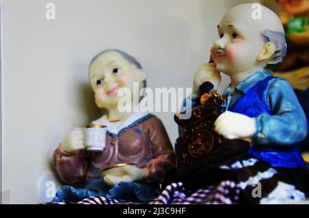 Souvenirs toys and vintage resin grandfather old man doll and retro grandmother senior woman on shelf for show in local gifts shop for thai people tra Stock Photo