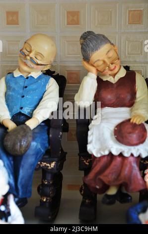 Souvenirs toys and vintage resin grandfather old man doll and retro grandmother senior woman on shelf for show in local gifts shop for thai people tra Stock Photo