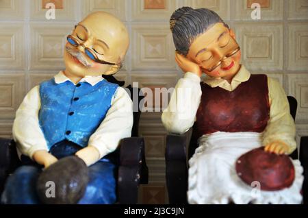 Souvenirs toys and vintage resin grandfather old man doll and retro grandmother senior woman on shelf for show in local gifts shop for thai people tra Stock Photo