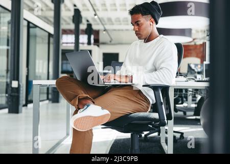 Focused programmer working on a new code. Creative young businessman working on a laptop while sitting alone in a modern workplace. Young businessman Stock Photo