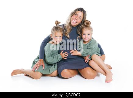 Two cute little sisters on the floor with pregnant mother Stock Photo