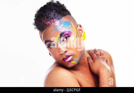 I am who I am. Portrait of a gender fluid young man wearing face paint against a white background. Stock Photo