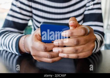 Cropped unrecognizable African American female in casual wear text messaging on cellphone Stock Photo