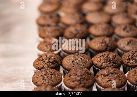 From above soft focus of many tasty chocolate cupcakes arranged in rows on table in bakery Stock Photo