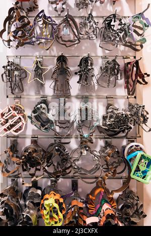 Bunch of biscuit cutters of various shapes hanging on rack on wall in bakery Stock Photo