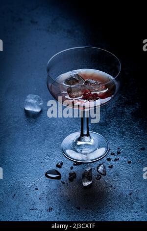 From above glass goblet of red wine with cubes of ice placed on wet table at night Stock Photo