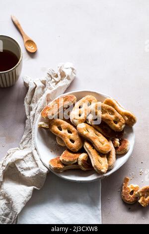 From above bunch of fresh tasty pretzels served in bowl near napkins and cup of coffee on gray table during breakfast in morning Stock Photo