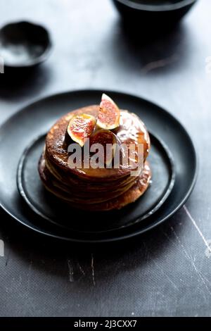 From above stack of yummy pancakes with maple syrup and fig slices served for breakfast on plate on gray table in morning Stock Photo