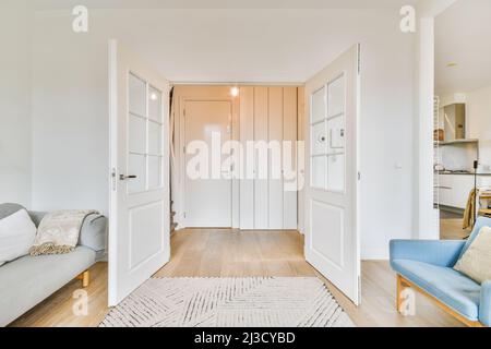 Opened doors of light living room with rug and comfortable couch with sofa placed in stylish apartment with glowing light Stock Photo