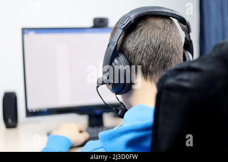Man in headset sitting at desktop PC and working in text editor. Concept of office work, support service, document editing, report preparation Stock Photo