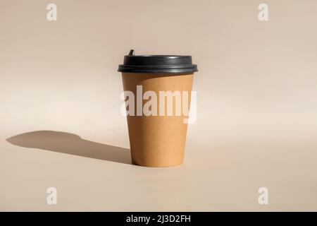 One Brown coffee paper cup. Mock-up with lid. Set of craft paper cups for coffee or tea on beige background. Disposable Recycled cups Stock Photo