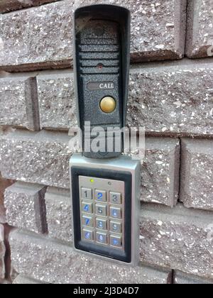 Coded electronic lock with a numeric keypad on a brick decorative wall at the entrance to the building Stock Photo