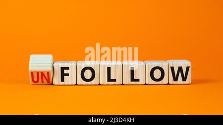 Follow or unfollow symbol. Turned wooden cubes and changed concept words Follow to Unfollow. Beautiful orange table orange background. Business and fo Stock Photo