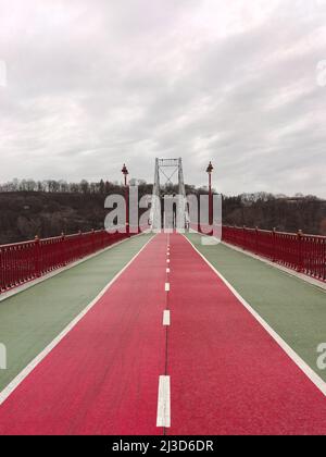 Asphalt divided road of red color on the bridge in perspective. Lampposts on the sides Stock Photo