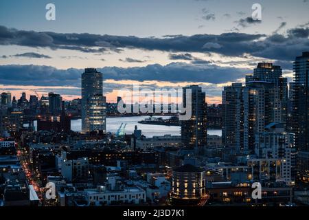 View of the lower Manhattan/Brooklyn skyline as the sun sets, taken from a rooftop in Williamsburg, Brooklyn, New York, United States of America (USA) Stock Photo