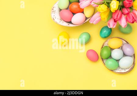 Easter eggs decoration with colorful tulip flowers on yellow paper background Stock Photo