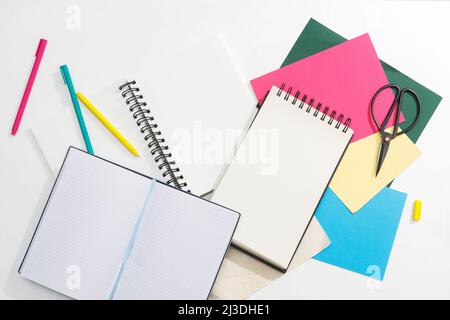 A lot of notebooks on springs, multi-colored paper: blue, red, green, gold, pens and scissors. Office concept. Place for text Stock Photo