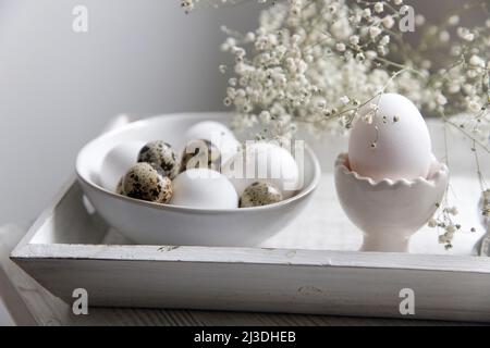 Table decorated for Easter in beige tones. Dried gypsophila, chicken and quail eggs and a cup of coffee. Easter concept. Stock Photo