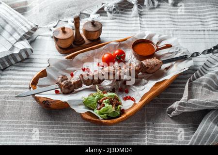 Barbecue with tomatoes and herbs on a wooden plate with paper Stock Photo