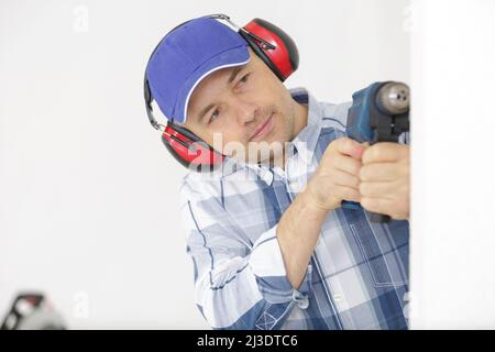 builder wearing protective workwear and holding electric drill Stock Photo