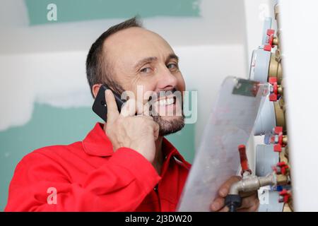 technician on the phone inspecting heating system in boiler room Stock Photo